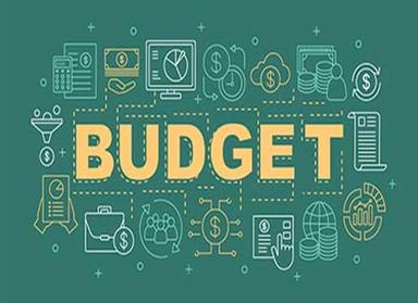 A Nigerian woman reviewing her monthly budget and expenses on a laptop while calculating savings and household costs amid rising living expenses.
